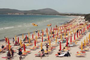 An inviting beach in Alghero, Sardinia, filled with vibrant umbrellas and sunbathers.