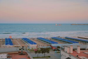 A peaceful beach scene with blue sunshades lined up along the shoreline during sunset.