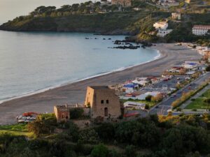 Aerial view of a coastal beach and historic ruins at sunset, featuring stunning natural beauty.