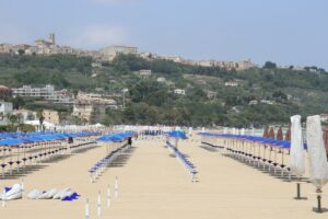Rows of empty beach chairs and umbrellas facing town.