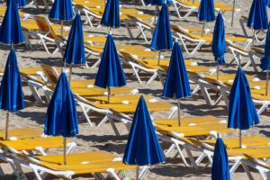 Empty sun loungers with blue umbrellas on a sunny beach, ideal for vacation and travel themes.