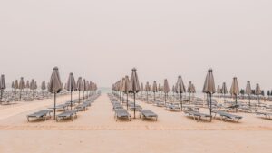 Serene view of empty beach in Rethymno, Greece with aligned sunbeds and umbrellas.