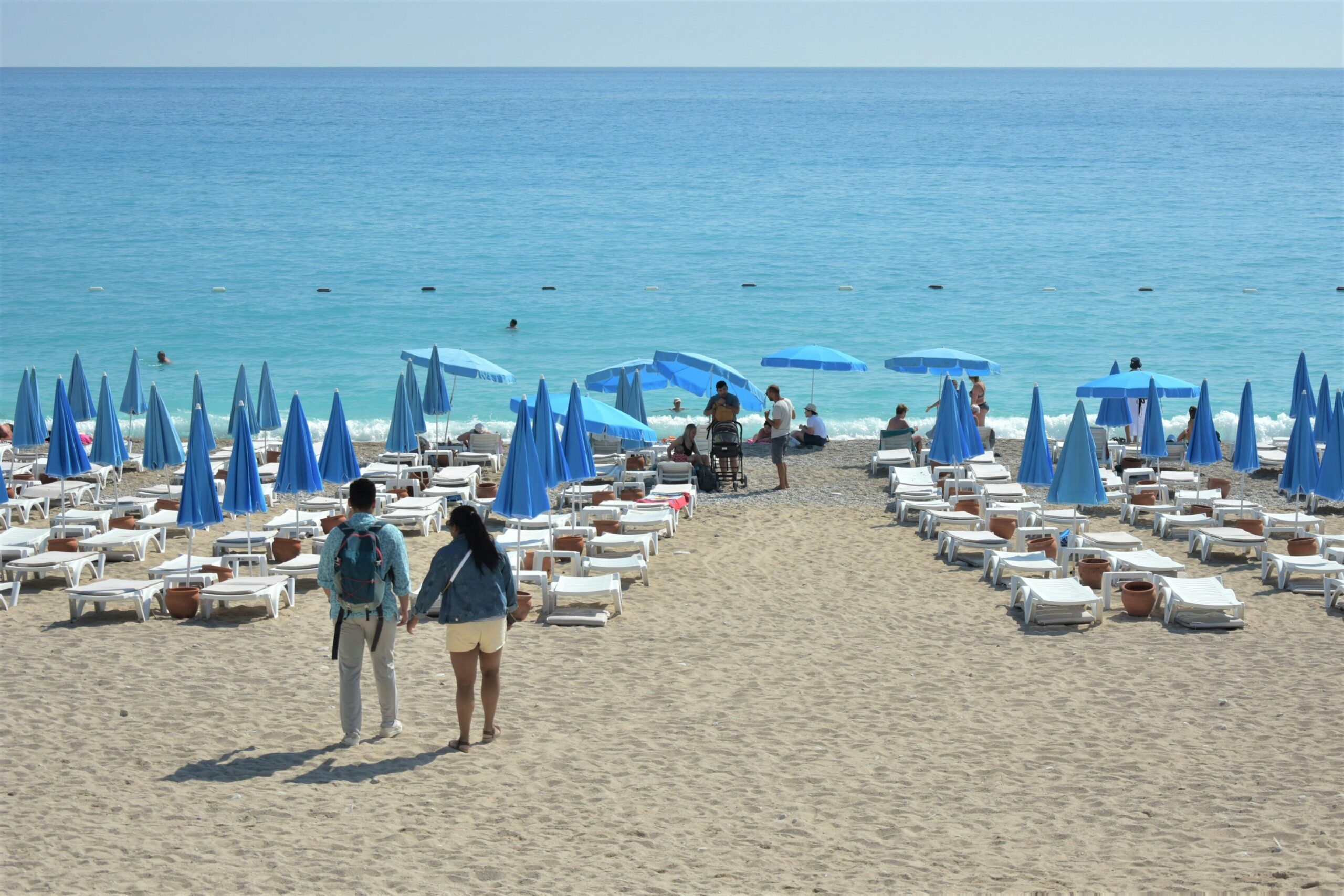 a couple of people walking down a sandy beach