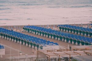 View of vibrant beach huts and striped umbrellas lining a serene beach by the ocean.