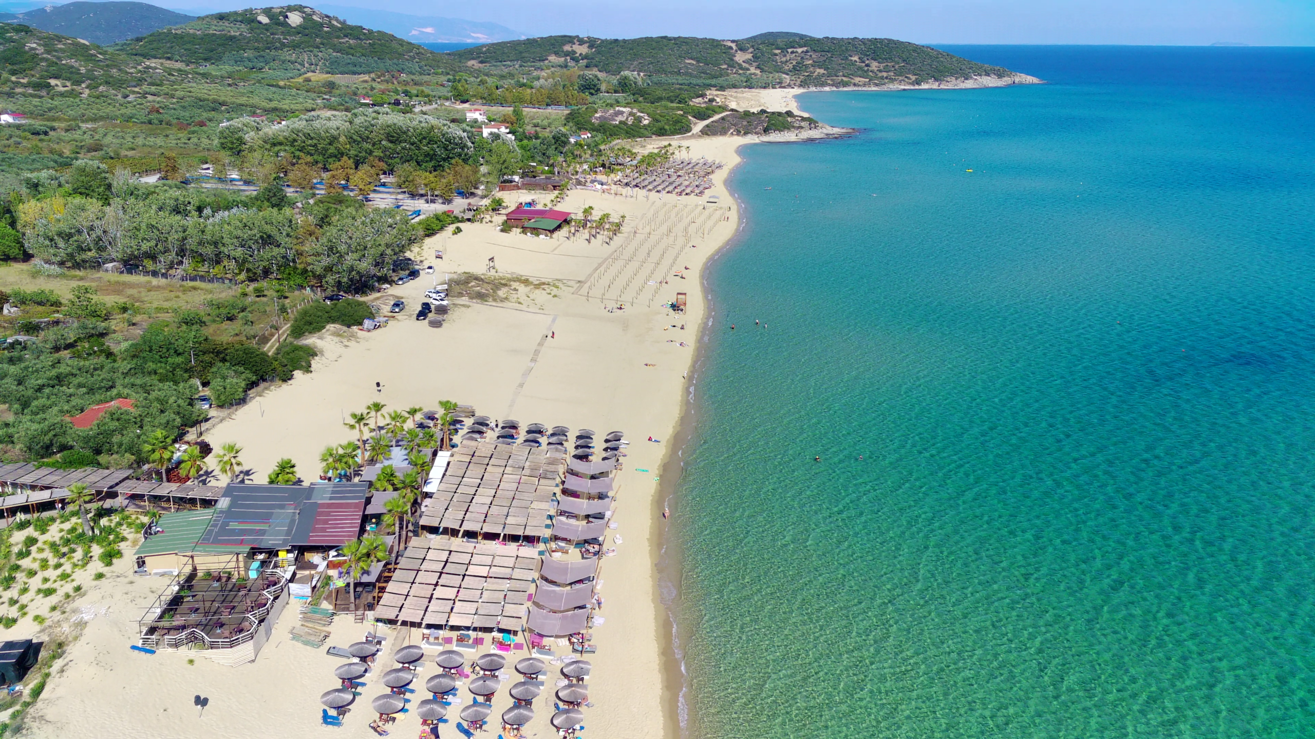Drone shot of a serene beach with sunbeds and clear blue water, perfect for a summer getaway.