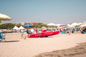 Scenic view of Venedik, Italy's sandy beach with vibrant umbrellas and lifeguard boat.