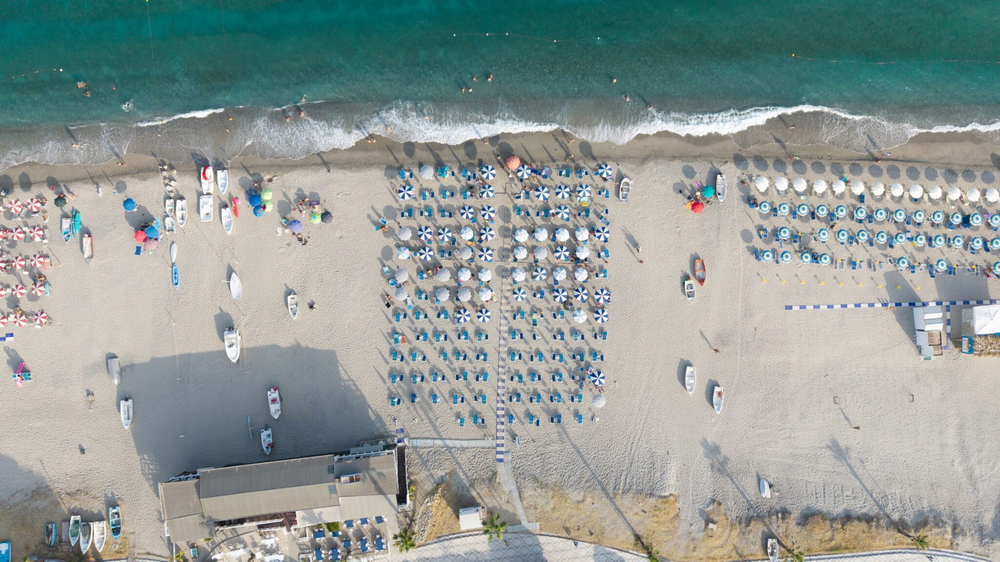 Stunning aerial image of Montepaone Lido beach in Calabria, Italy, showcasing vibrant umbrellas and clear sea waters.