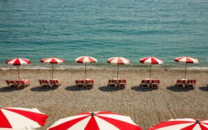Empty beach with deckchairs and umbrellas near wavy sea on sunny day in summer